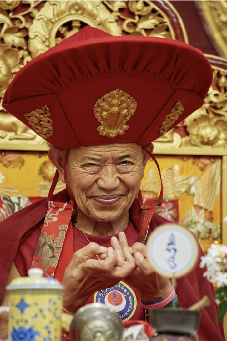 Kyabje Garchen Rinpoche smiling in ceremonial red hat