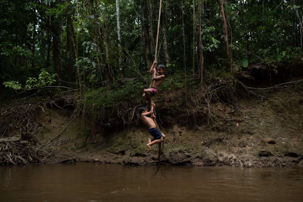 Children swinging on a rope over the river